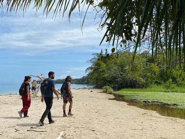 Eine Gruppe Menschen beim Spaziergang an einem Sandstrand am Meer.